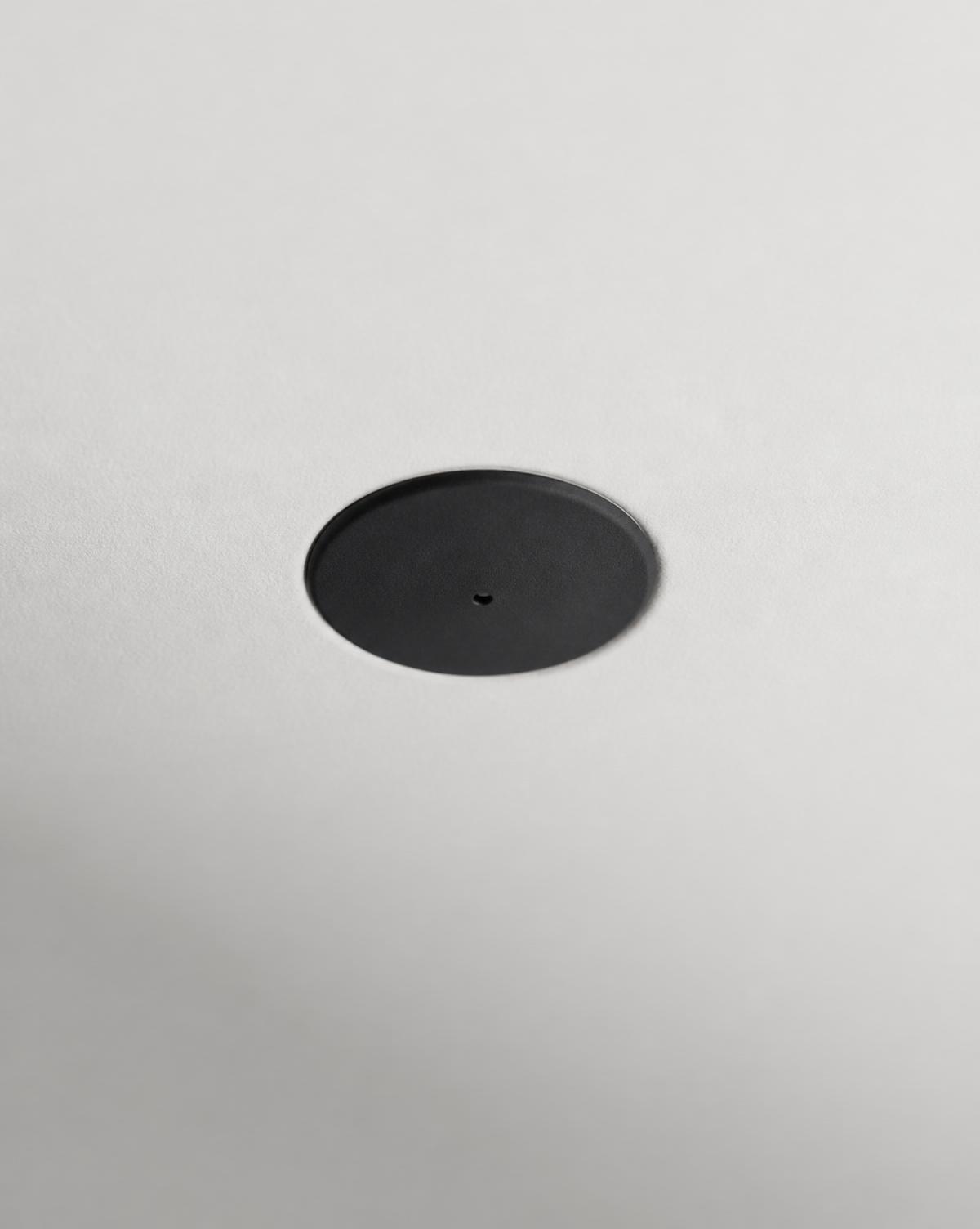 Almost invisible black disc sensor flush in a white ceiling